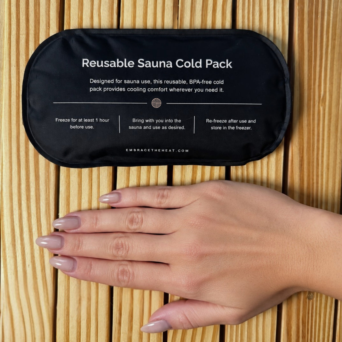 Embrace reusable sauna cold pack shown next to a hand for size comparison on a wooden sauna bench.