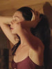 Woman putting on a black sauna hat during a sauna session.