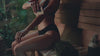 Woman using a wooden body gua sha during a sauna ritual.